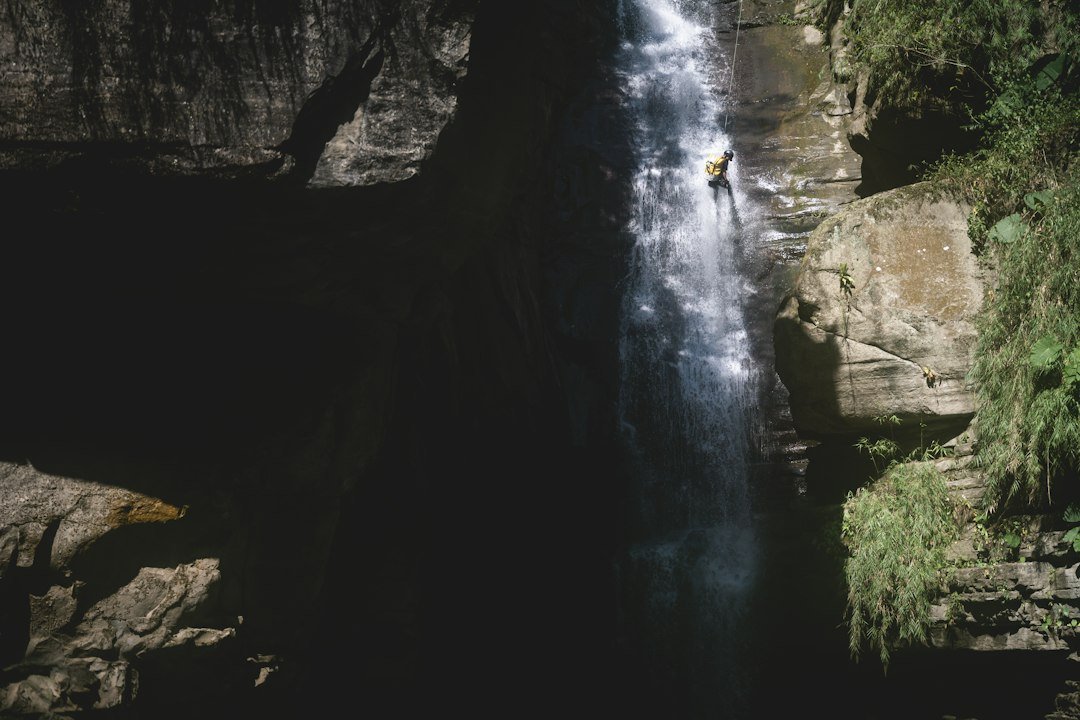 Waterval, rotsen en abseilende persoon