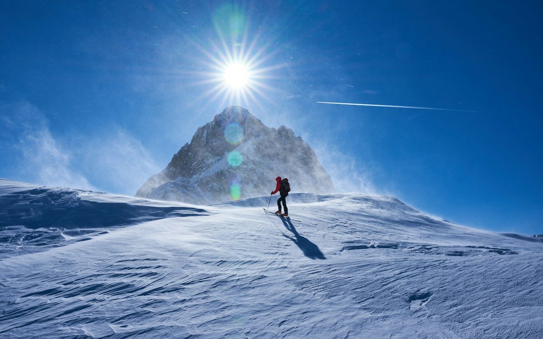 Persoon in sneeuw, berg en zon
